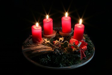 Ein Adventskranz mit vier angezündeten Kerzen